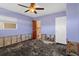 Bedroom with damaged walls and flooring features a ceiling fan, natural light, and access to an ensuite bathroom at 4630 W Bay Villa Ave, Tampa, FL 33611