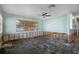 Bright living room showing large window and ceiling fan with damage to the bottom of walls needing to be repaired at 4630 W Bay Villa Ave, Tampa, FL 33611