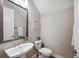 Neutral powder room featuring a pedestal sink, toilet, mirror, and light fixture at 5086 San Martino Dr, Wesley Chapel, FL 33543