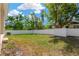 Large backyard featuring a white vinyl fence, lush grass, and mature trees with bright blue skies and fluffy white clouds at 860 17Th S Ave, St Petersburg, FL 33701