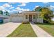 Charming home features a manicured lawn, brick driveway, attached garage and red front door at 860 17Th S Ave, St Petersburg, FL 33701