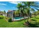 Beautiful backyard with a screened-in swimming pool, green lawn, and palm trees, creating a private oasis at 8621 Bridgewater Dr, New Port Richey, FL 34655