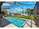 Sparkling swimming pool enclosed in a screened lanai with a clear blue sky above a manicured backyard at 8621 Bridgewater Dr, New Port Richey, FL 34655