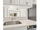 Modern kitchen featuring stainless steel sink, white cabinets, and open view to living space at 10423 Carrollbrook Cir # 102, Tampa, FL 33618