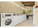 On-site laundry room with multiple machines, bright lighting, and a cheerful mural with a tropical theme at 10423 Carrollbrook Cir # 102, Tampa, FL 33618