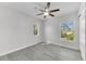 Bright bedroom with gray wood-look floors, a modern ceiling fan, and lots of natural light from two windows at 10906 Johanna Ave, Riverview, FL 33578