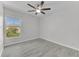 This bedroom features light gray walls, wood-look flooring, a ceiling fan, and a bright window at 10906 Johanna Ave, Riverview, FL 33578
