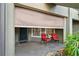 Cozy front porch with privacy shade, two red chairs and decorative mushrooms in the landscape at 13714 Messina Loop # 101, Bradenton, FL 34211