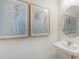 Stylish powder room with modern pedestal sink, framed art, and an elegant round mirror at 15120 Cuzcorro Ct, Nokomis, FL 34275