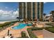View of the uniquely shaped pool with surrounding lounge chairs and beach access and high rise in the background at 1520 Gulf Blvd # Ph2, Clearwater Beach, FL 33767