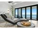 Relax in this luxurious main bedroom featuring a lounger and ocean views through glass doors at 1906 Carolina Ne Ave, St Petersburg, FL 33703
