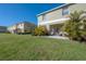 The backyard has a green lawn and comfortable seating on the patio with trees behind the water at 20319 Starfinder Way, Tampa, FL 33647