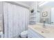 Bathroom with shower/tub, floral curtain, decorative shelves, and cream vanity at 2448 Enterprise Rd # 5, Clearwater, FL 33763