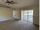 Spacious living room features neutral carpet, sliding glass doors, and a ceiling fan at 26348 Crooked Tree Ln, Brooksville, FL 34602