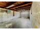 Unfinished basement with concrete floor, cinder block walls, wooden ceiling beams, and an access door to the outside at 325 Orangeview Ave, Clearwater, FL 33755