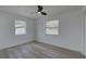 Bright bedroom featuring light-colored laminate floors, a modern ceiling fan, and dual windows offering plenty of natural light at 417 Hollyhock Ln, Spring Hill, FL 34606