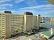 A sunny, ground-level view of the condominium building showing parking, the main entrance, and well-manicured landscaping at 4525 Cove Cir # 304, St Petersburg, FL 33708