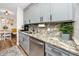 Modern kitchen featuring grey cabinets, stainless steel appliances, a decorative backsplash, and granite countertops at 455 Alt 19 S # 162, Palm Harbor, FL 34683