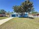 Charming blue home featuring a covered carport and a large tree in the front yard at 4716 Town N Country Blvd, Tampa, FL 33615