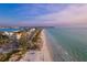 Picturesque aerial view of a sunny beach with clear water, adjacent to quaint buildings and a coastal road at 4801 Osprey S Dr # 404, St Petersburg, FL 33711