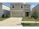 Charming two-story home features a beige stucco exterior, well-manicured lawn, and a two-car garage at 5764 Hollingworth Trl, Wesley Chapel, FL 33545
