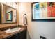 Stylish powder room with a granite countertop, framed mirror, and palm tree artwork at 6531 Spring Oak Ct, Tampa, FL 33625