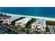 Breathtaking aerial view of beachfront condos, a pristine white beach, and the sparkling turquoise ocean at 6600 Sunset Way # 112, St Pete Beach, FL 33706