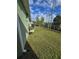 Wide view of the backyard with grass, showing the exterior of a green house with a chain-link fence at 6704 Hickorywood Ln # 2B, New Port Richey, FL 34653