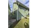Side exterior of a home with green siding and small patio, showing minimal landscaping at 6704 Hickorywood Ln # 2B, New Port Richey, FL 34653