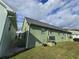 Exterior of a home with green siding showing minimal landscaping, patio area, and drainage at 6704 Hickorywood Ln # 2B, New Port Richey, FL 34653