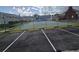 View of a tennis court with green surface, surrounded by a chain-link fence and parking spaces at 6704 Hickorywood Ln # 2B, New Port Richey, FL 34653