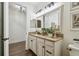 Bathroom showcasing granite counters, cream colored cabinets, wood tile flooring, and a white door at 8307 Bluevine Sky Dr, Land O Lakes, FL 34637