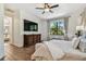 Inviting bedroom with wood floors, a large window, and a decorative dresser beneath a wall-mounted TV at 8307 Bluevine Sky Dr, Land O Lakes, FL 34637