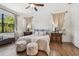 Bright bedroom with a ceiling fan, two windows, wood floors, and tasteful decor at 8307 Bluevine Sky Dr, Land O Lakes, FL 34637