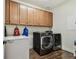 Laundry room with washer, dryer, freezer, wooden cabinets, and wood tile floors for an attractive and functional space at 8307 Bluevine Sky Dr, Land O Lakes, FL 34637
