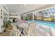 Enclosed pool area featuring a partial outdoor kitchen, dining furniture, ceiling fans, and bright light at 9339 Creole Ct, Weeki Wachee, FL 34613