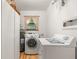 Bright laundry room with modern washer, dryer, water heater, wooden floors, and storage at 9466 127Th Ave, Largo, FL 33773