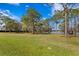 Expansive grassy yard extends towards a serene lake, framed by mature trees and lush surroundings at 10101 Tarpon Springs Rd, Odessa, FL 33556