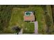 Aerial view of a home with an enclosed pool surrounded by greenery and a well-kept lawn at 10603 1St St, Riverview, FL 33569