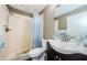 Cozy bathroom featuring a shower with blue patterned curtain, a white toilet, and a dark vanity with white sink at 10603 1St St, Riverview, FL 33569