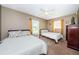 Neutral bedroom featuring two beds, a ceiling fan, and bright windows with orange curtains at 10603 1St St, Riverview, FL 33569