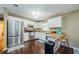 Bright kitchen featuring white cabinetry, stainless steel appliances, breakfast bar, and hardwood floors at 10603 1St St, Riverview, FL 33569