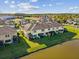 Aerial view of lakeside townhomes featuring manicured backyards overlooking a community lake on a sunny, partly cloudy day at 11641 Crowned Sparrow Ln, Tampa, FL 33626