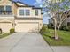 Two-story tan home with a well-maintained lawn, two car garage, and lush landscaping at 11641 Crowned Sparrow Ln, Tampa, FL 33626