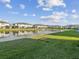 Beautiful lakeside townhomes with lush green lawns and a central fountain feature under a sunny, partly cloudy sky at 11641 Crowned Sparrow Ln, Tampa, FL 33626