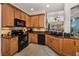 Modern kitchen features wood cabinets, black appliances, and a view of the bright, spacious living room at 13207 San Blas Loop, Largo, FL 33774
