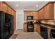 Bright kitchen with stainless steel refrigerator, wooden cabinets, tile backsplash, and modern black appliances at 13207 San Blas Loop, Largo, FL 33774