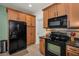 Bright kitchen featuring stainless steel refrigerator, wooden cabinets, and modern black appliances at 13207 San Blas Loop, Largo, FL 33774