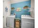 The laundry room is equipped with a washer, dryer, shelving and a blue accent wall at 13207 San Blas Loop, Largo, FL 33774