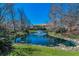 Overlook of a tranquil pond and fountain, bordered by bare trees, grassy areas, and rocks at 13207 San Blas Loop, Largo, FL 33774